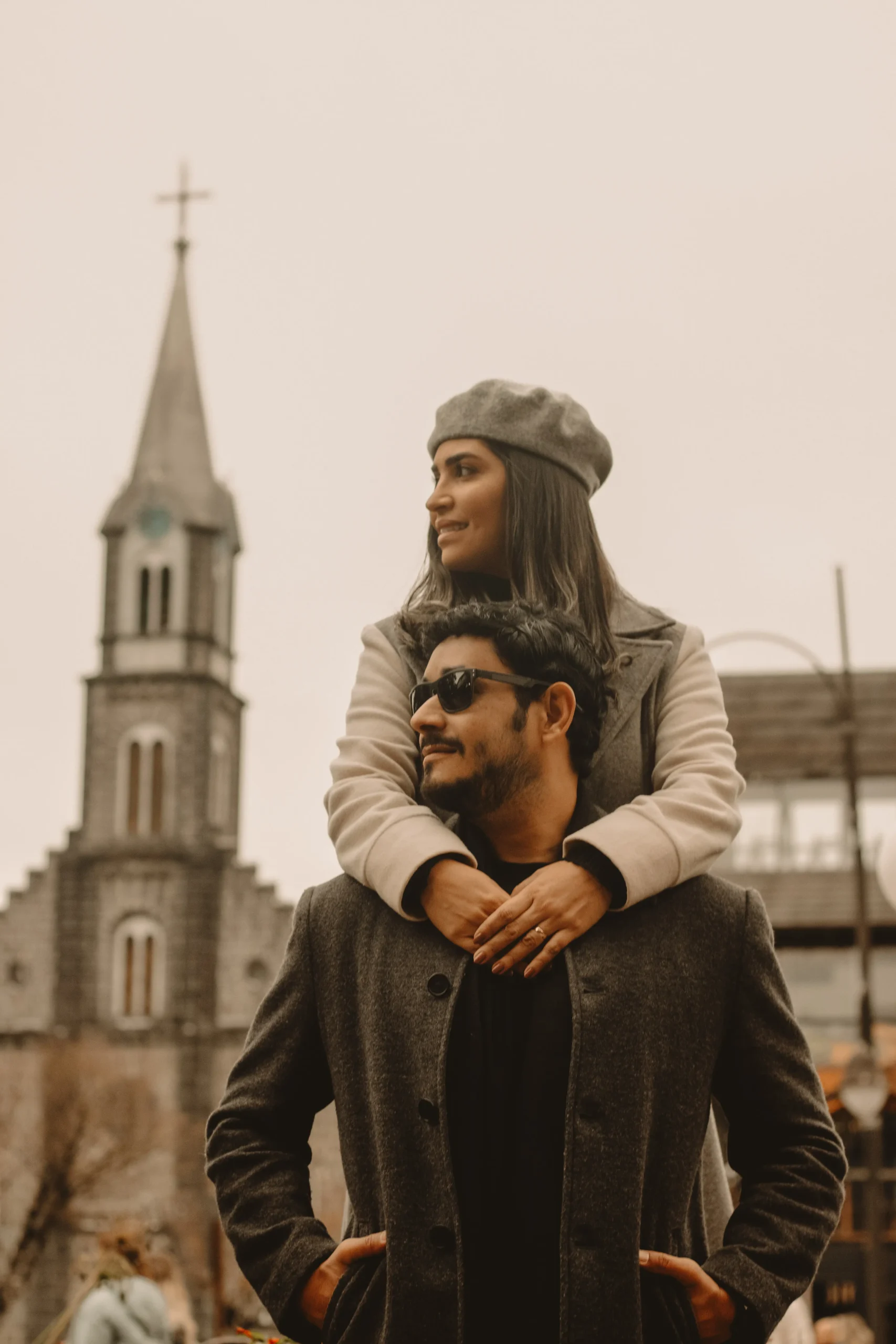 Casal em ensaio fotográfico romântico em Gramado, com a Igreja São Pedro ao fundo